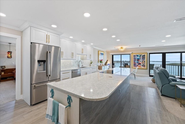 kitchen featuring white cabinets, decorative backsplash, ornamental molding, stainless steel appliances, and a sink