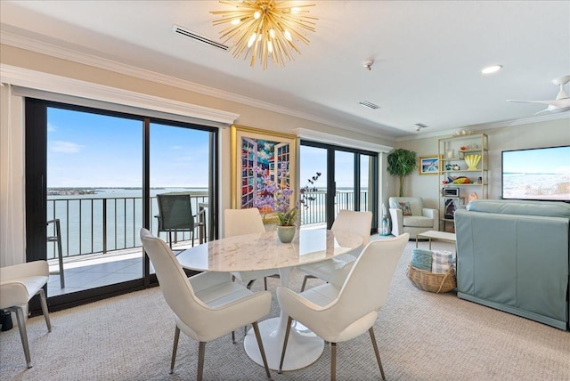 carpeted dining space featuring a water view, visible vents, ornamental molding, and a notable chandelier