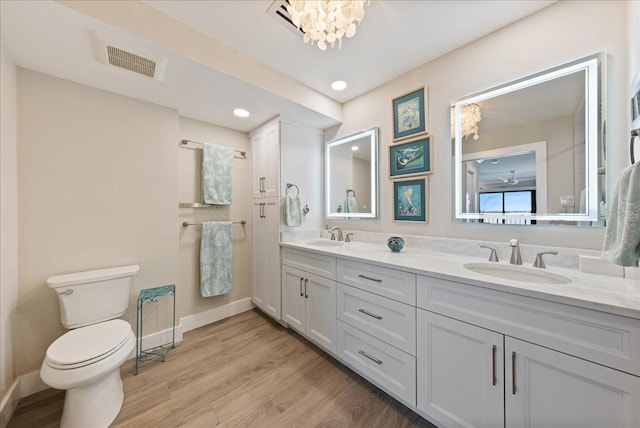 bathroom featuring toilet, visible vents, a sink, and wood finished floors