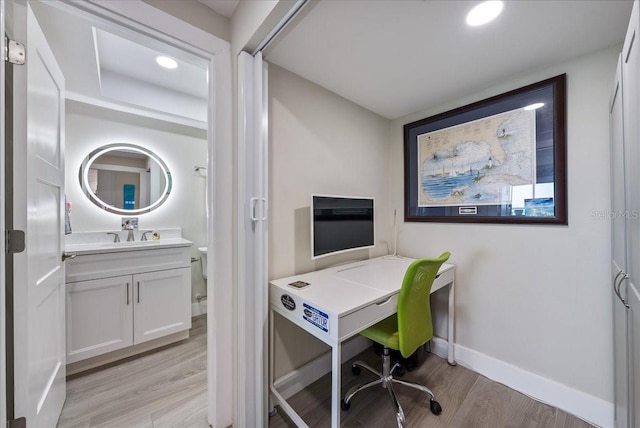 office space with light wood-type flooring, a sink, baseboards, and recessed lighting