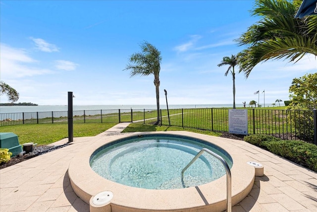 view of pool with fence, a community hot tub, and a lawn