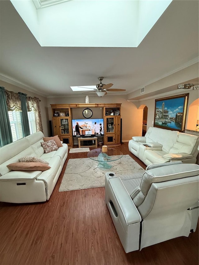 living room featuring visible vents, a skylight, wood finished floors, ceiling fan, and crown molding