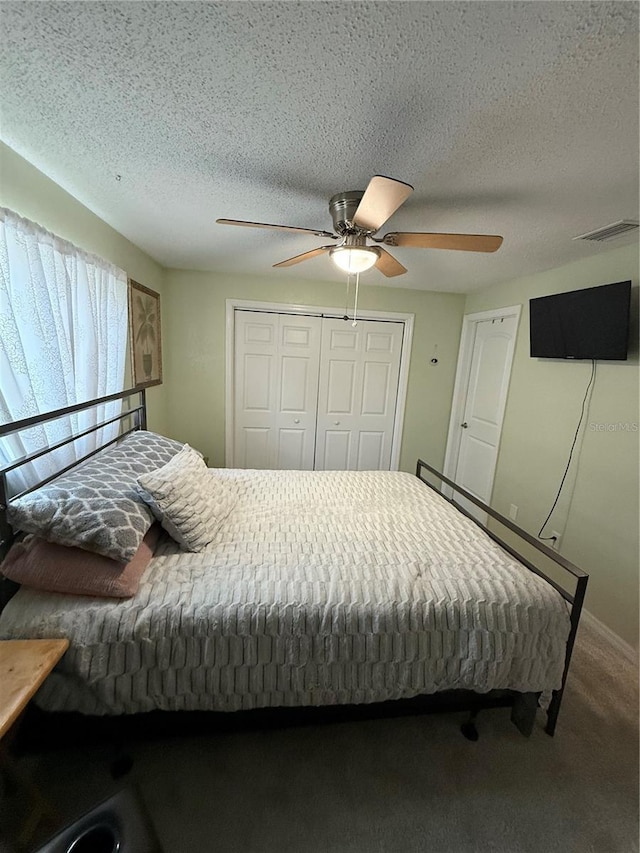 carpeted bedroom featuring a ceiling fan, visible vents, a textured ceiling, and a closet