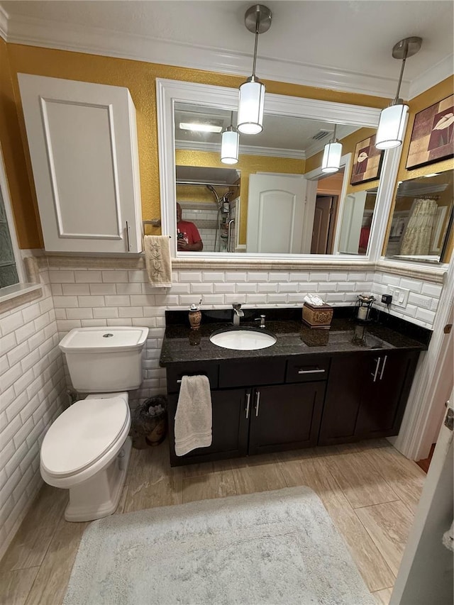 bathroom with wood finished floors, toilet, vanity, ornamental molding, and decorative backsplash