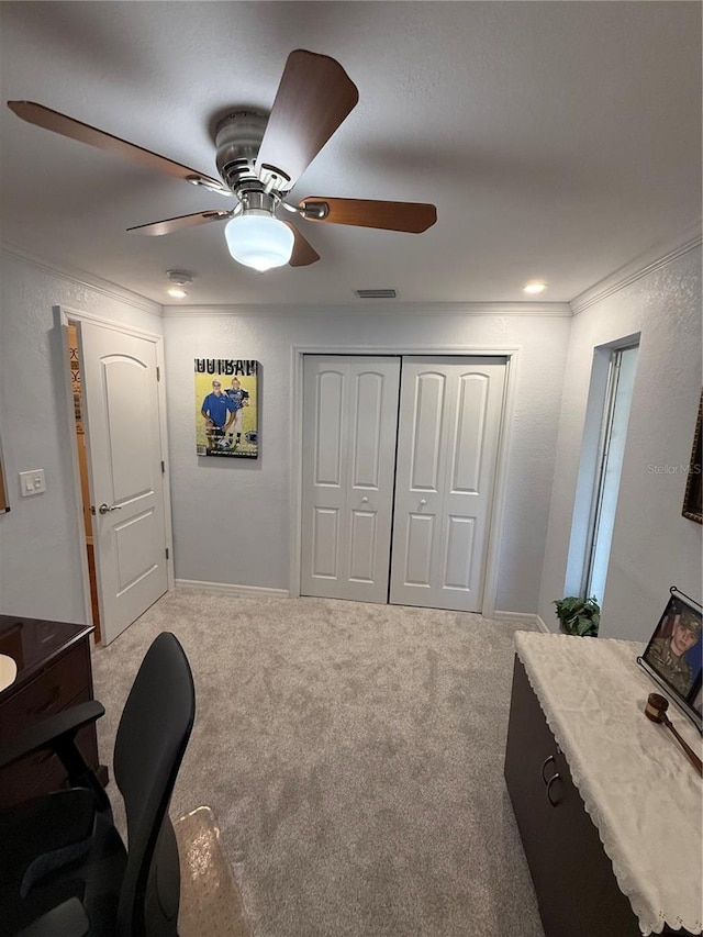 carpeted office featuring a ceiling fan, visible vents, and crown molding
