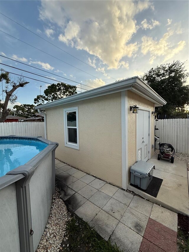 view of side of property with a patio, a fenced backyard, a fenced in pool, and stucco siding