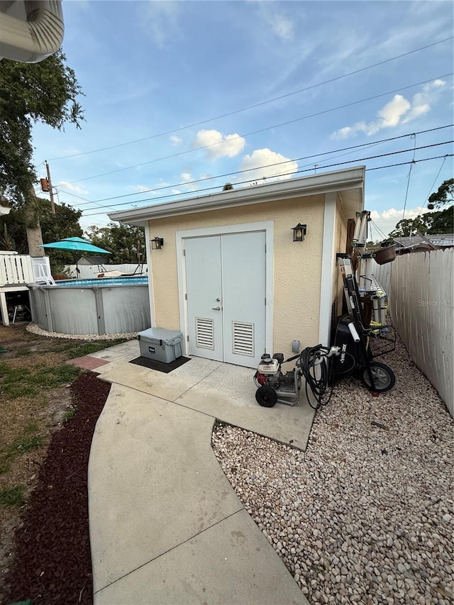 view of outbuilding with fence, a fenced in pool, and an outdoor structure