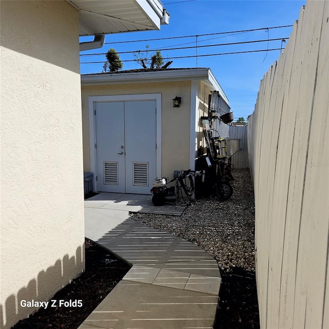doorway to property featuring french doors, stucco siding, and fence