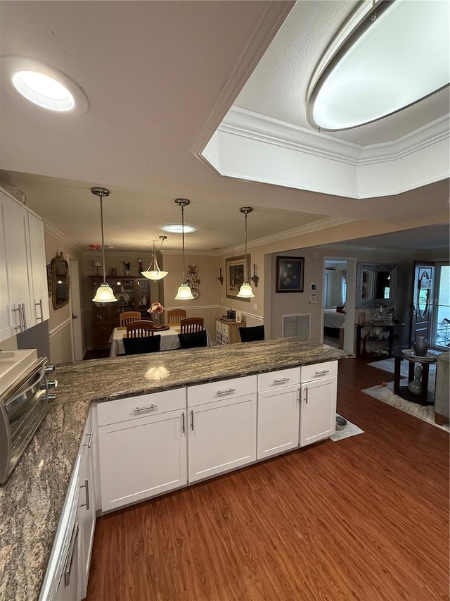 kitchen featuring white cabinets, a peninsula, a toaster, dark wood finished floors, and crown molding