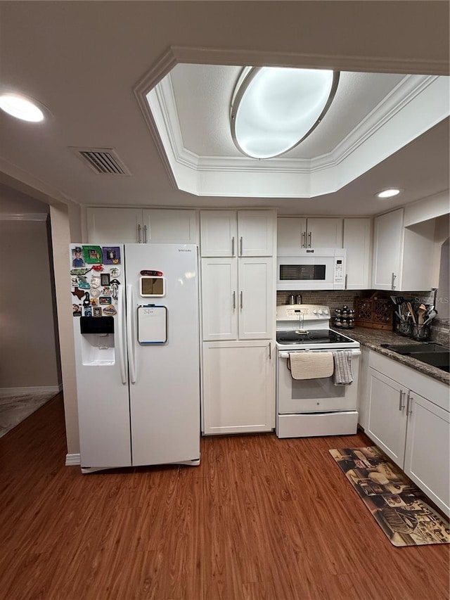 kitchen featuring wood finished floors, visible vents, ornamental molding, and white appliances