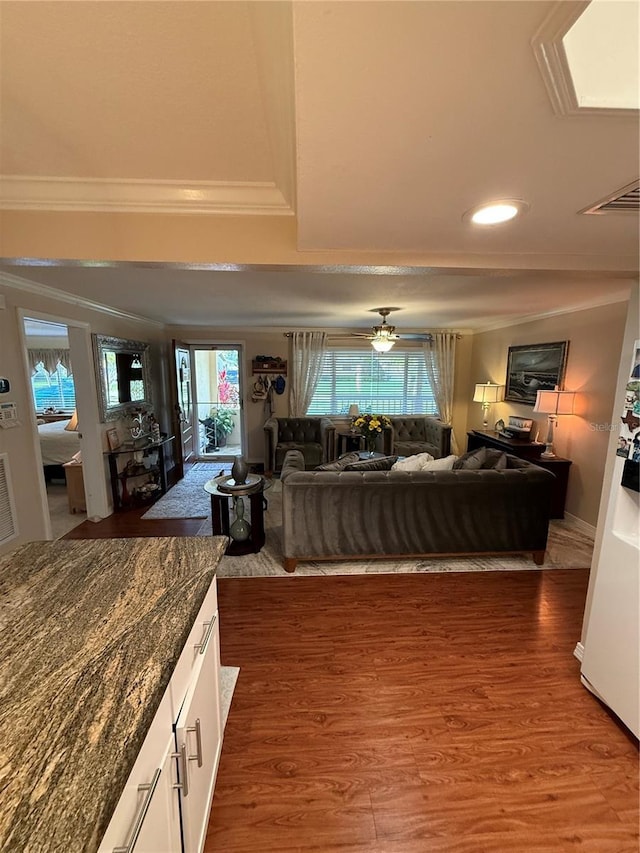 living area with recessed lighting, crown molding, wood finished floors, and a healthy amount of sunlight