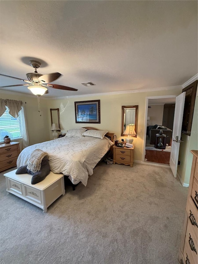 bedroom with a textured ceiling, ceiling fan, light colored carpet, ornamental molding, and visible vents