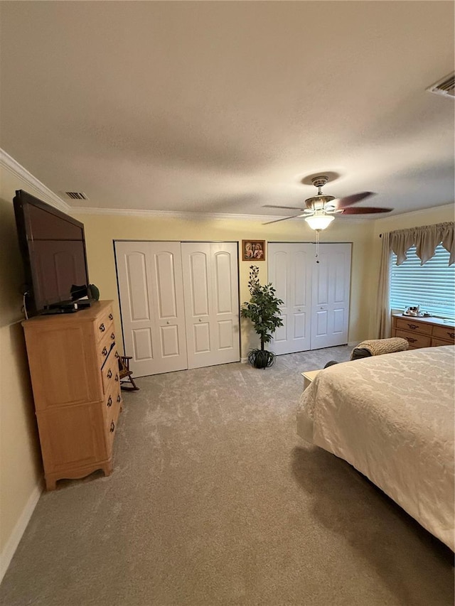 bedroom with multiple closets, visible vents, and carpet