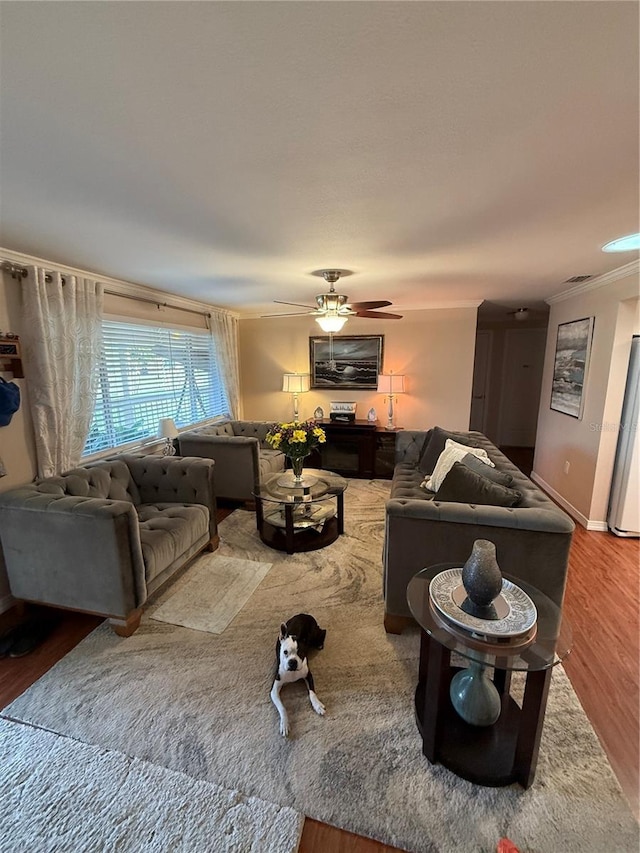 living area featuring crown molding, wood finished floors, ceiling fan, baseboards, and visible vents