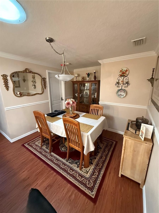dining space featuring baseboards, ornamental molding, wood finished floors, and visible vents