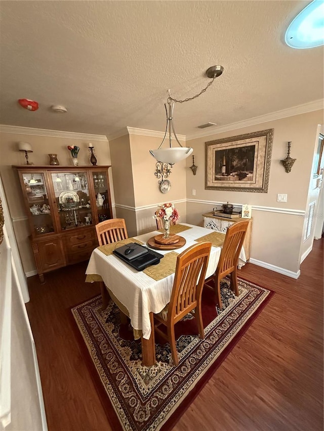 dining space featuring dark wood finished floors, a textured ceiling, crown molding, and baseboards