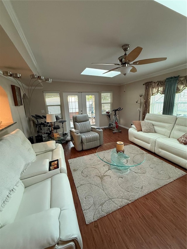 living area featuring wood finished floors, a ceiling fan, a skylight, and ornamental molding