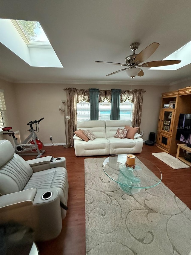 living room featuring a skylight, wood finished floors, ceiling fan, and crown molding