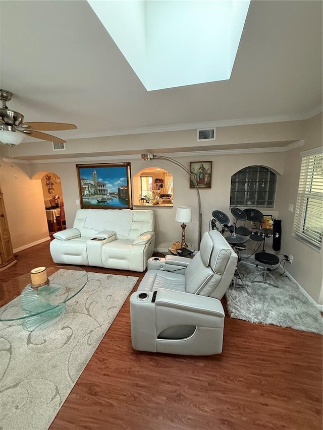 living room featuring crown molding, a skylight, arched walkways, baseboards, and visible vents