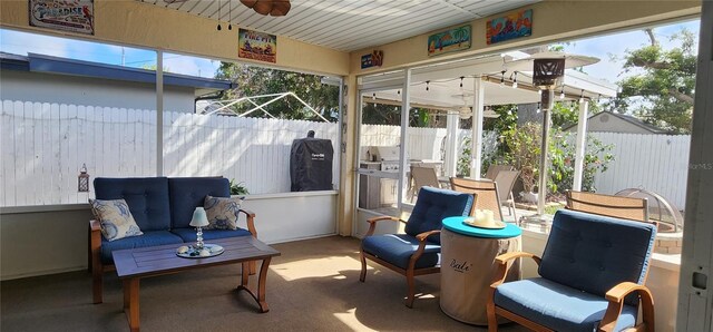 sunroom featuring an outdoor hangout area, a ceiling fan, and carpet