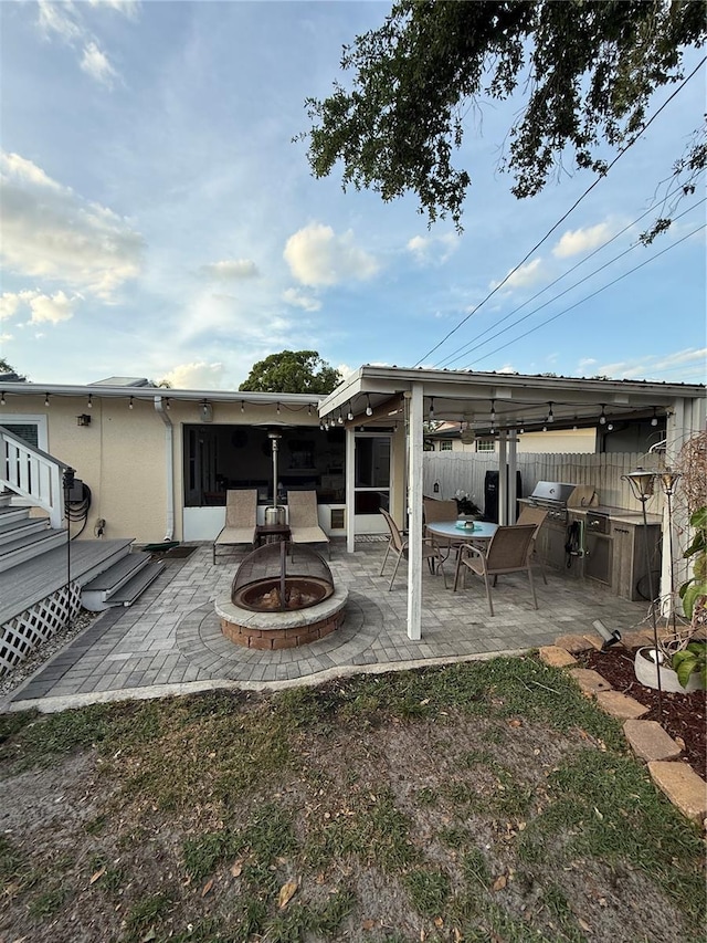 back of property with fence, a patio area, and an outdoor fire pit