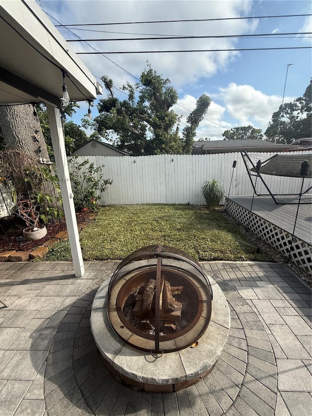view of yard with a fire pit, a patio area, a wooden deck, and a fenced backyard