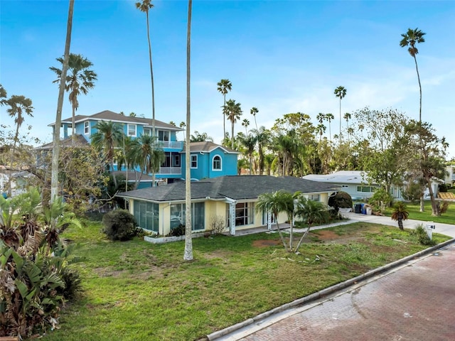 view of front of house with concrete driveway, a front yard, and a balcony