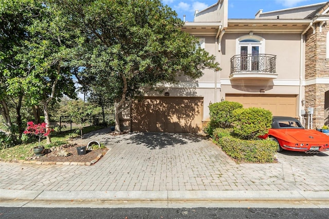 view of front of home featuring a garage, stone siding, decorative driveway, and stucco siding