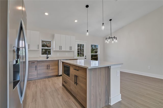 kitchen with light countertops, modern cabinets, a center island, and stainless steel fridge with ice dispenser