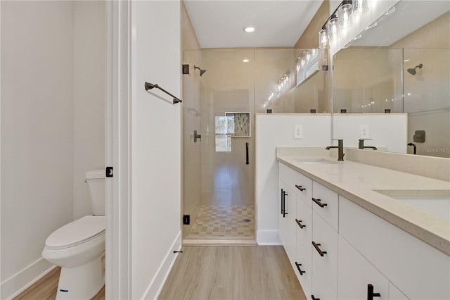 full bathroom with double vanity, a stall shower, toilet, wood finished floors, and a sink