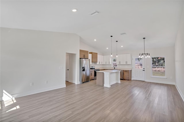 kitchen featuring a center island, stainless steel appliances, light countertops, visible vents, and open floor plan