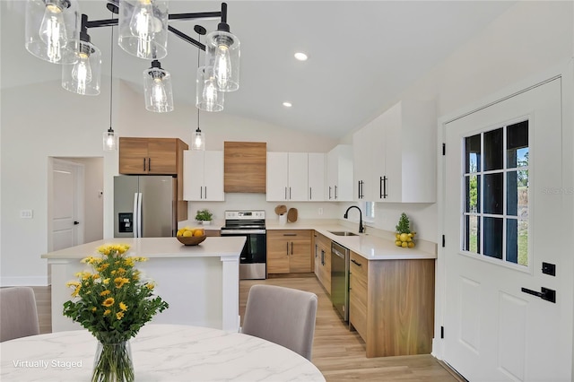 kitchen featuring stainless steel appliances, light countertops, vaulted ceiling, and wall chimney exhaust hood