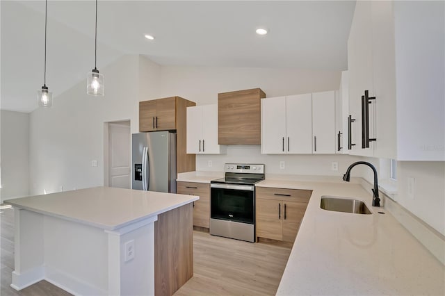 kitchen with light wood-style flooring, stainless steel appliances, a sink, light countertops, and pendant lighting