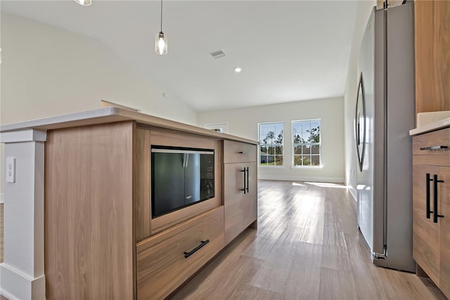 kitchen with visible vents, lofted ceiling, light wood-style flooring, modern cabinets, and freestanding refrigerator