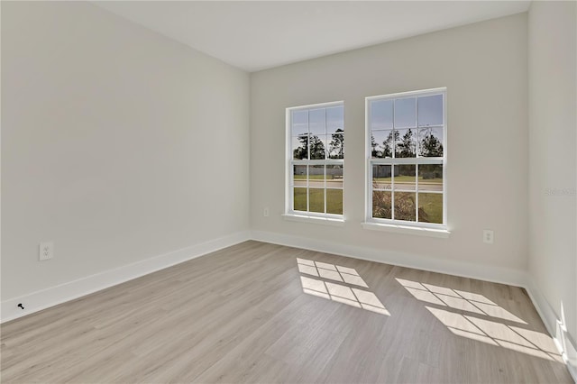 spare room with baseboards and wood finished floors