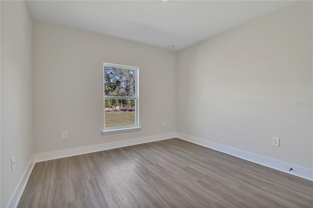 spare room with baseboards and wood finished floors