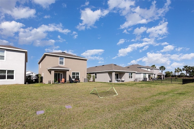 back of house featuring stucco siding, a yard, and fence