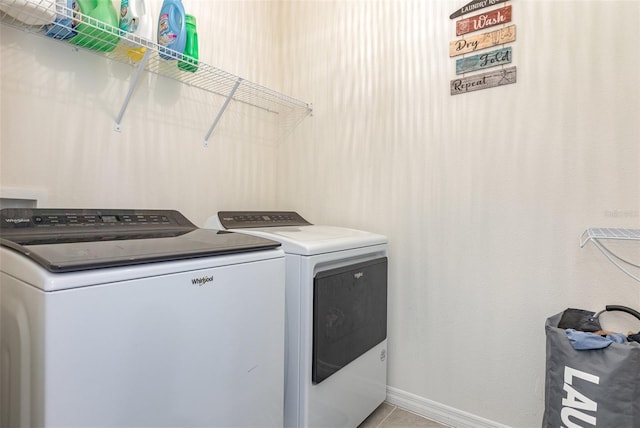 laundry area featuring laundry area, washing machine and dryer, baseboards, and light tile patterned flooring