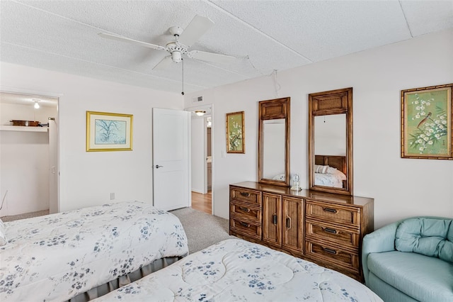 carpeted bedroom with a textured ceiling, visible vents, and a ceiling fan