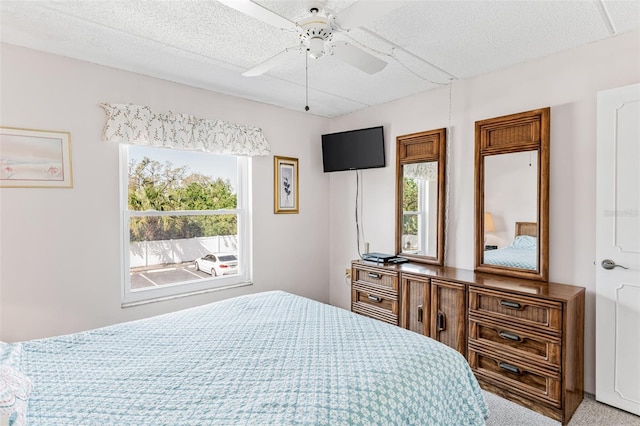 bedroom with light colored carpet, ceiling fan, and a textured ceiling
