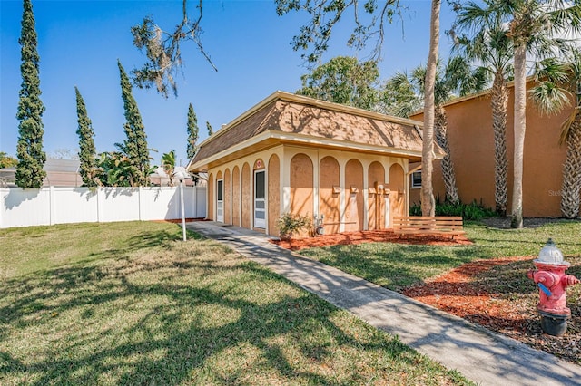 view of front of house with a front lawn, fence, and stucco siding