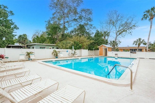 pool with a patio area, a fenced backyard, a storage shed, and an outdoor structure