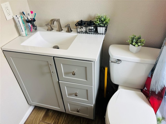 bathroom featuring toilet, hardwood / wood-style flooring, and vanity