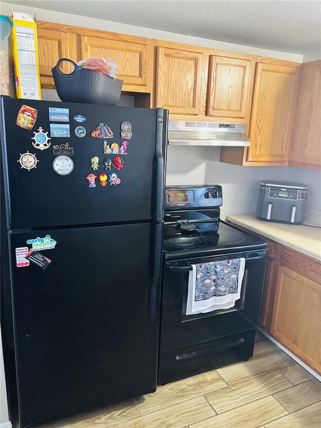 kitchen featuring light hardwood / wood-style flooring, a textured ceiling, and black appliances