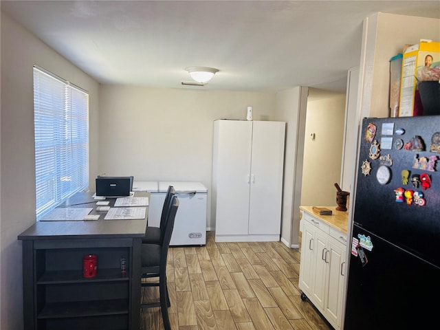 kitchen with black refrigerator, white cabinetry, and fridge