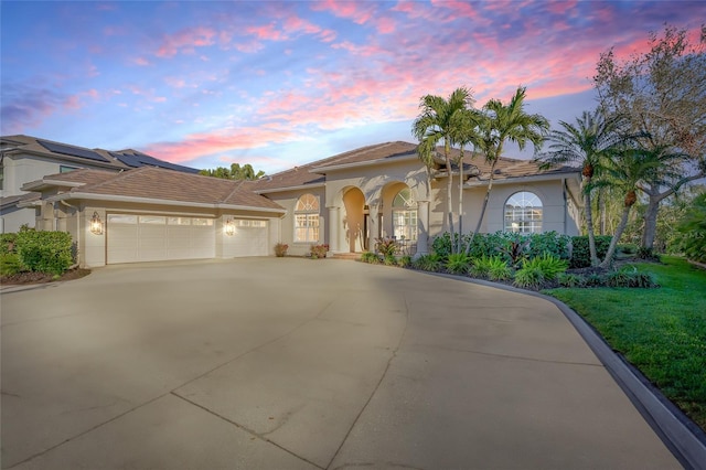 mediterranean / spanish-style home featuring concrete driveway, an attached garage, and stucco siding