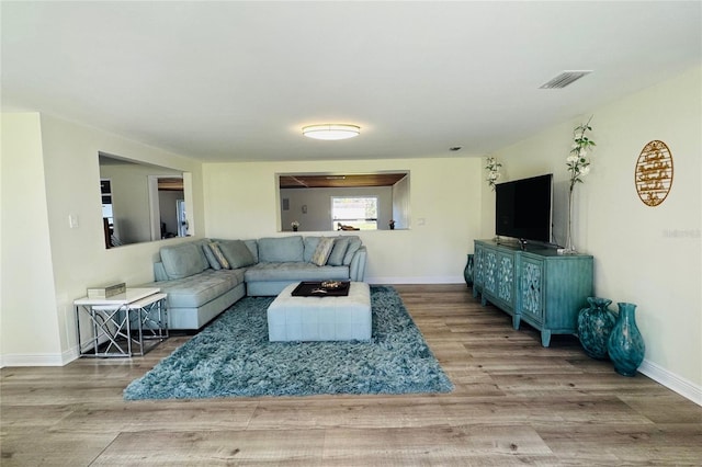 living area with baseboards, visible vents, and wood finished floors