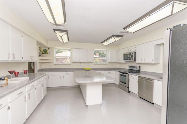 kitchen featuring stainless steel appliances, light countertops, white cabinetry, and a center island