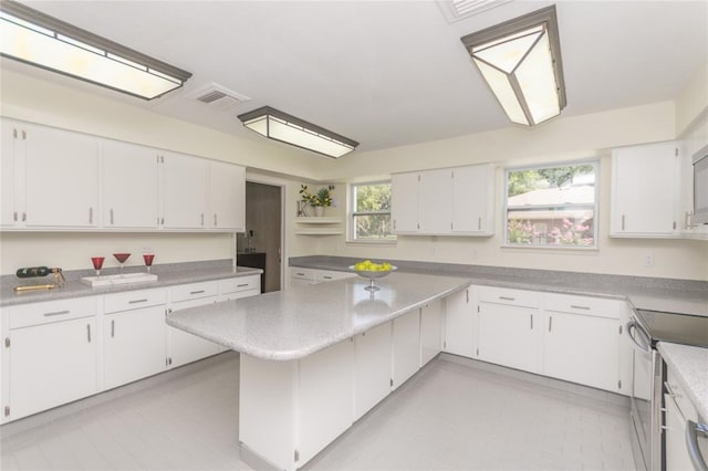 kitchen with visible vents, white cabinets, light countertops, and stainless steel range with electric cooktop