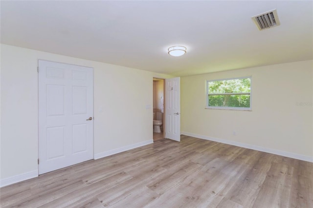 spare room with baseboards, visible vents, and light wood finished floors